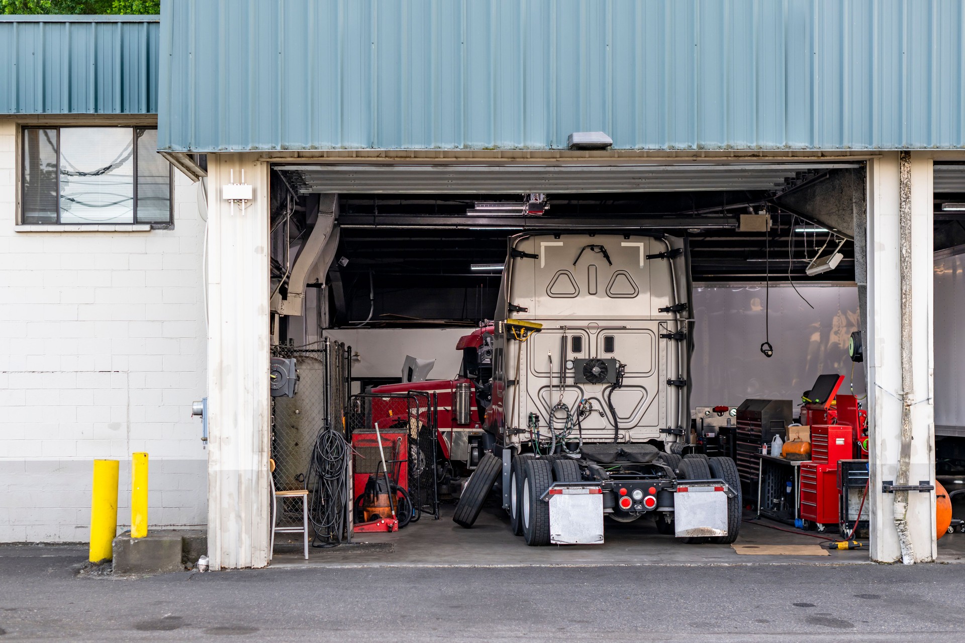 Broken big rig semi trucks tractors stand for repair and maintenance in a automotive repair shop